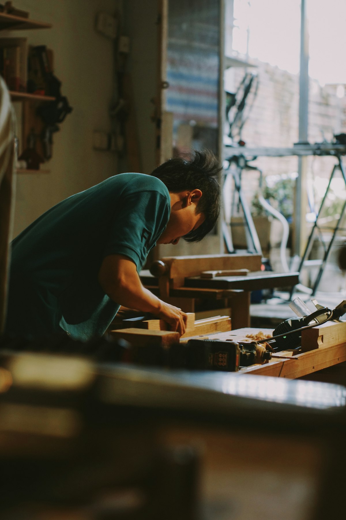 Carpenter working on timber at a workbench in a naturally lit workshop