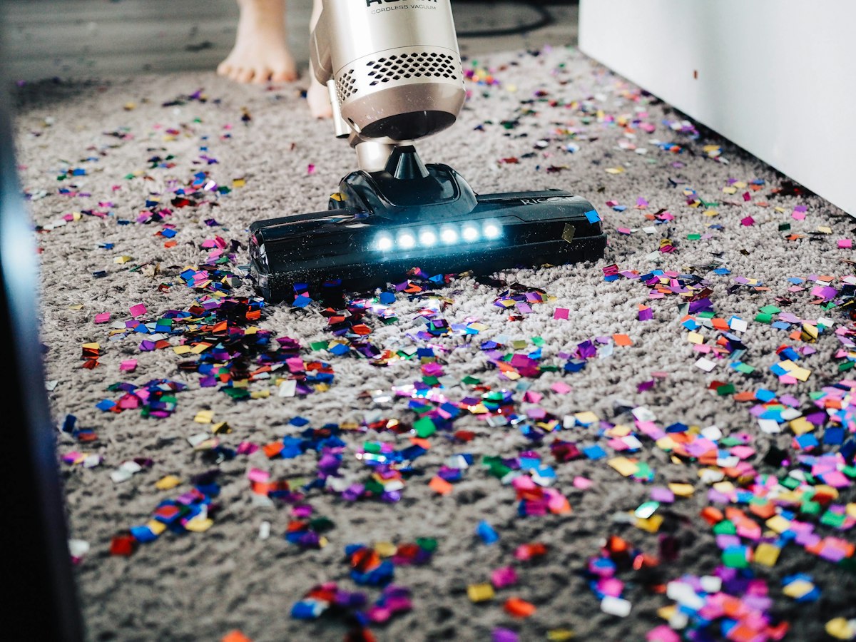 Vacuum cleaner removing confetti from a carpet during a home clean